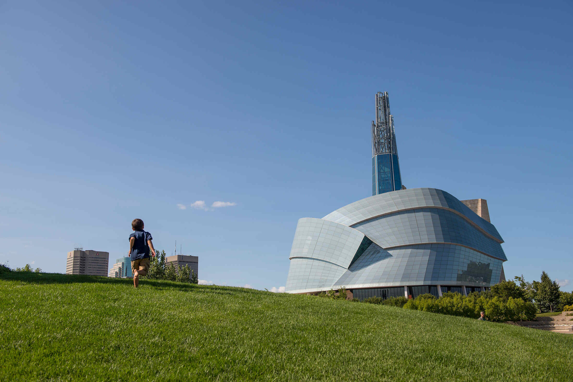 A child running on the grass in front of the Canadian Museum of Human rights