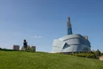 A child running on the grass in front of the Canadian Museum of Human rights