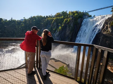 Couple stand on viewing platform and look out at Montmorency Falls