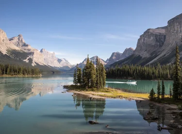 A small boat drives behind Spirit Island on Maligne Lake in the Rockies