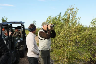 A man is looking through binoculars while standing next to a woman