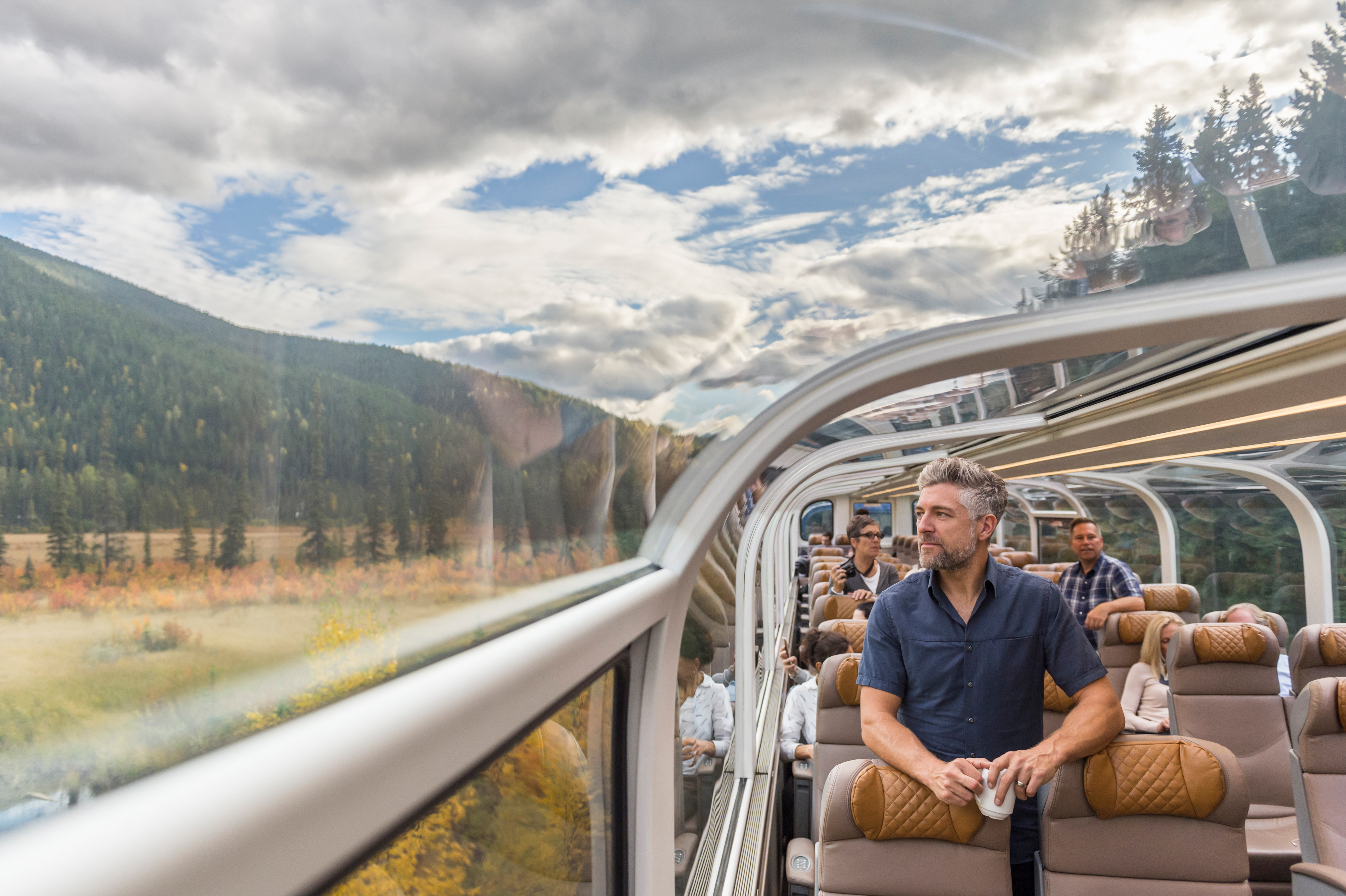 Man looks at the scenery from inside a GoldLeaf coach on Rocky Mountaineer train