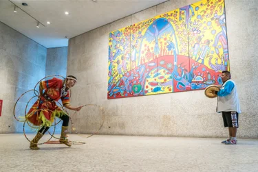 Two Indigenous people perform in traditional clothing at the Winnipeg Art Gallery in Manitoba