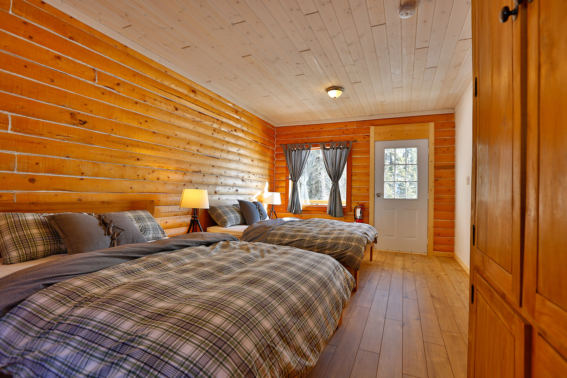 A bedroom in a log cabin with two beds and a door