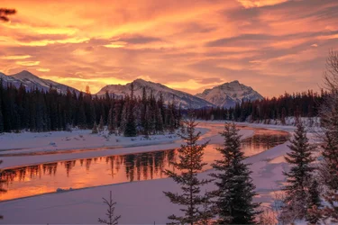 Sunrise through soft clouds mirrored in lake in Icefields Parkway