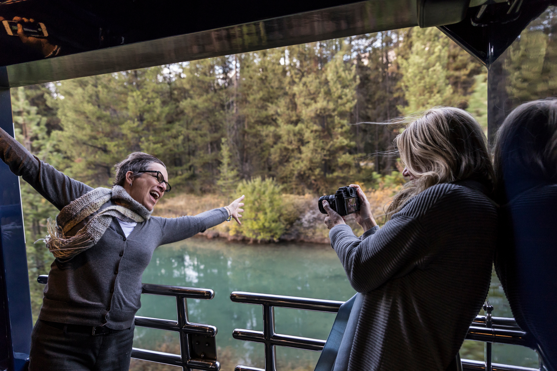Friends taking photos from the outdoor viewing platform of the GoldLeaf service coach