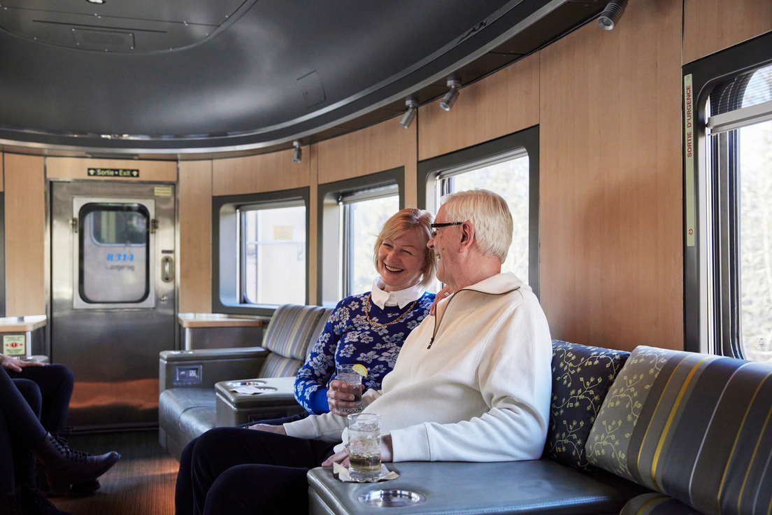 Couple enjoying a drink in the VIA Rail bullet lounge on The Canadian train