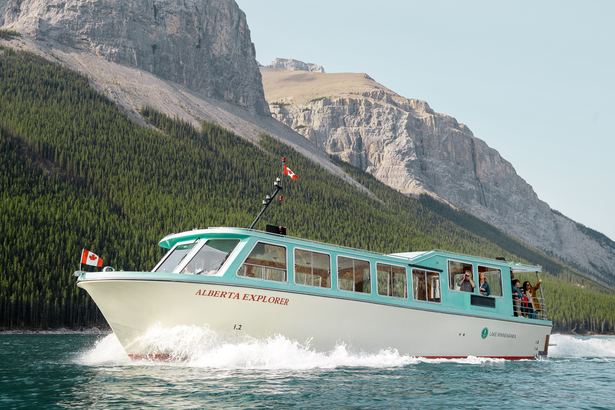 Close up shot of small boat cruising across Lake Minnewanka in Banff