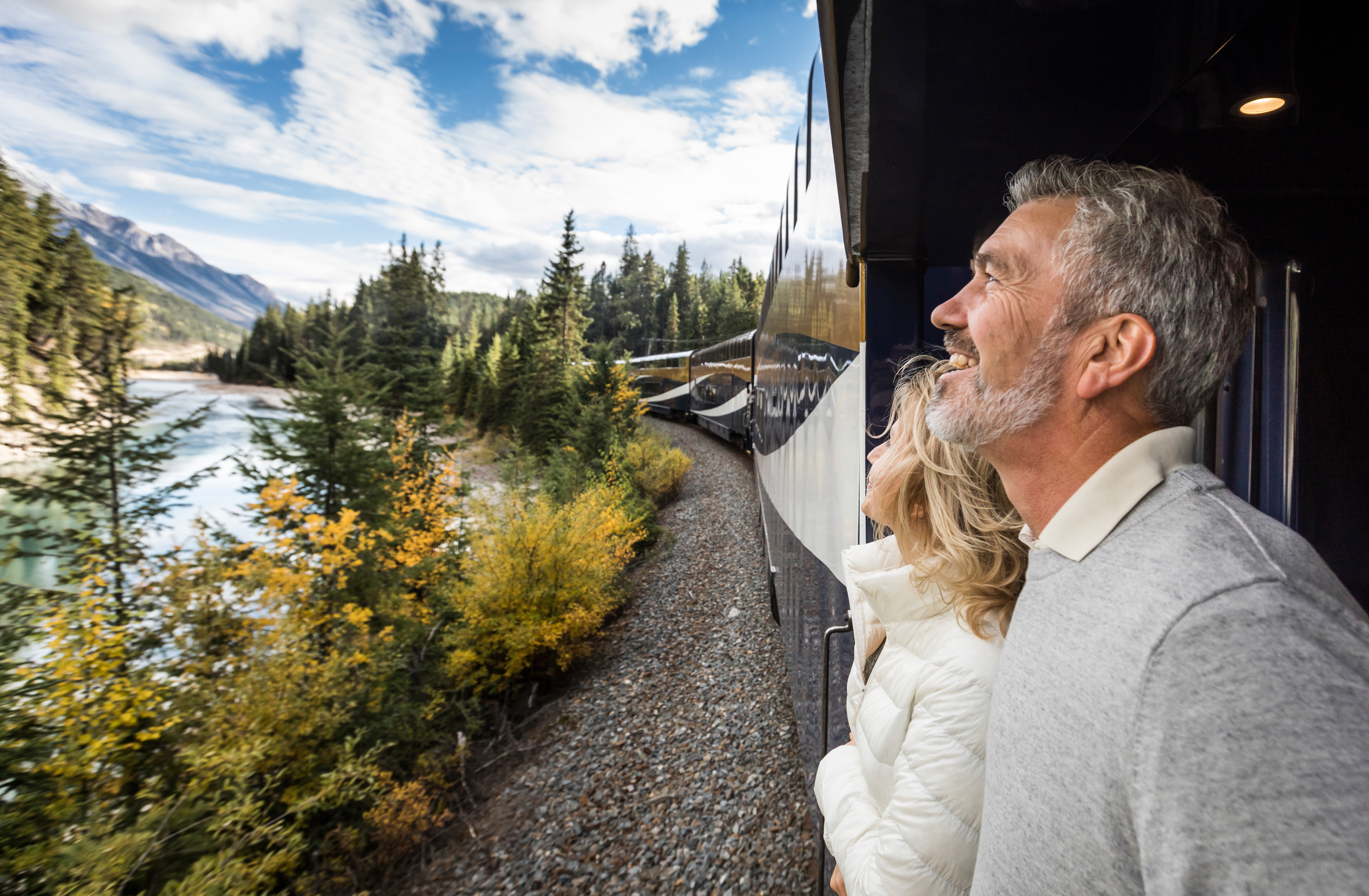 Couple enjoys the view from the GoldLeaf service outdoor viewing platform on Rocky Mountaineer train