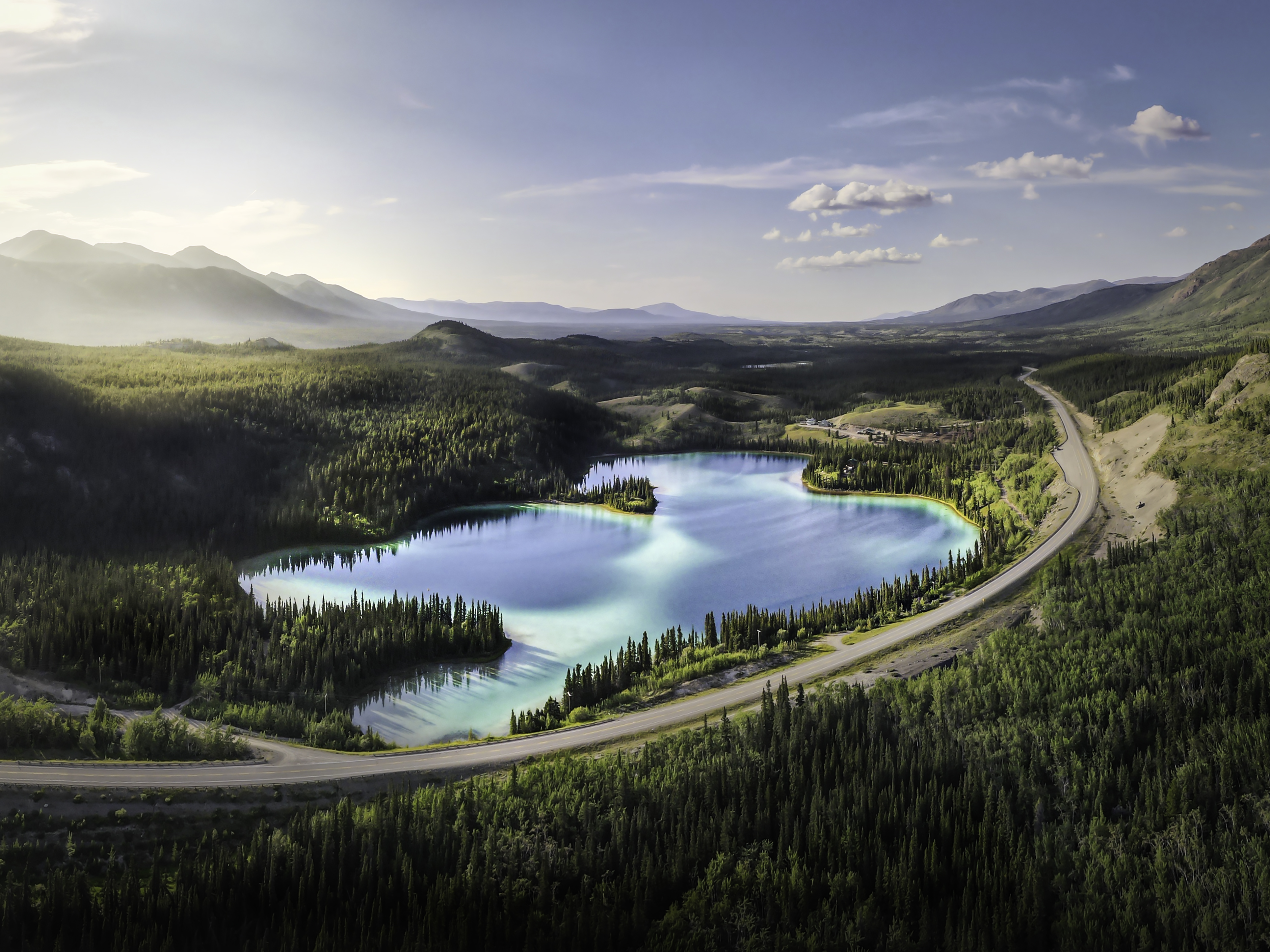 Aerial view of turquoise lake next to a highway in the Yukon