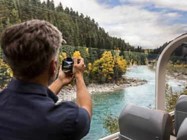 Man takes photo of scenic river from Rocky Mountaineer train car