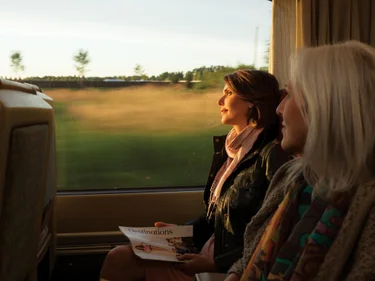 Two women riding the train at sunset