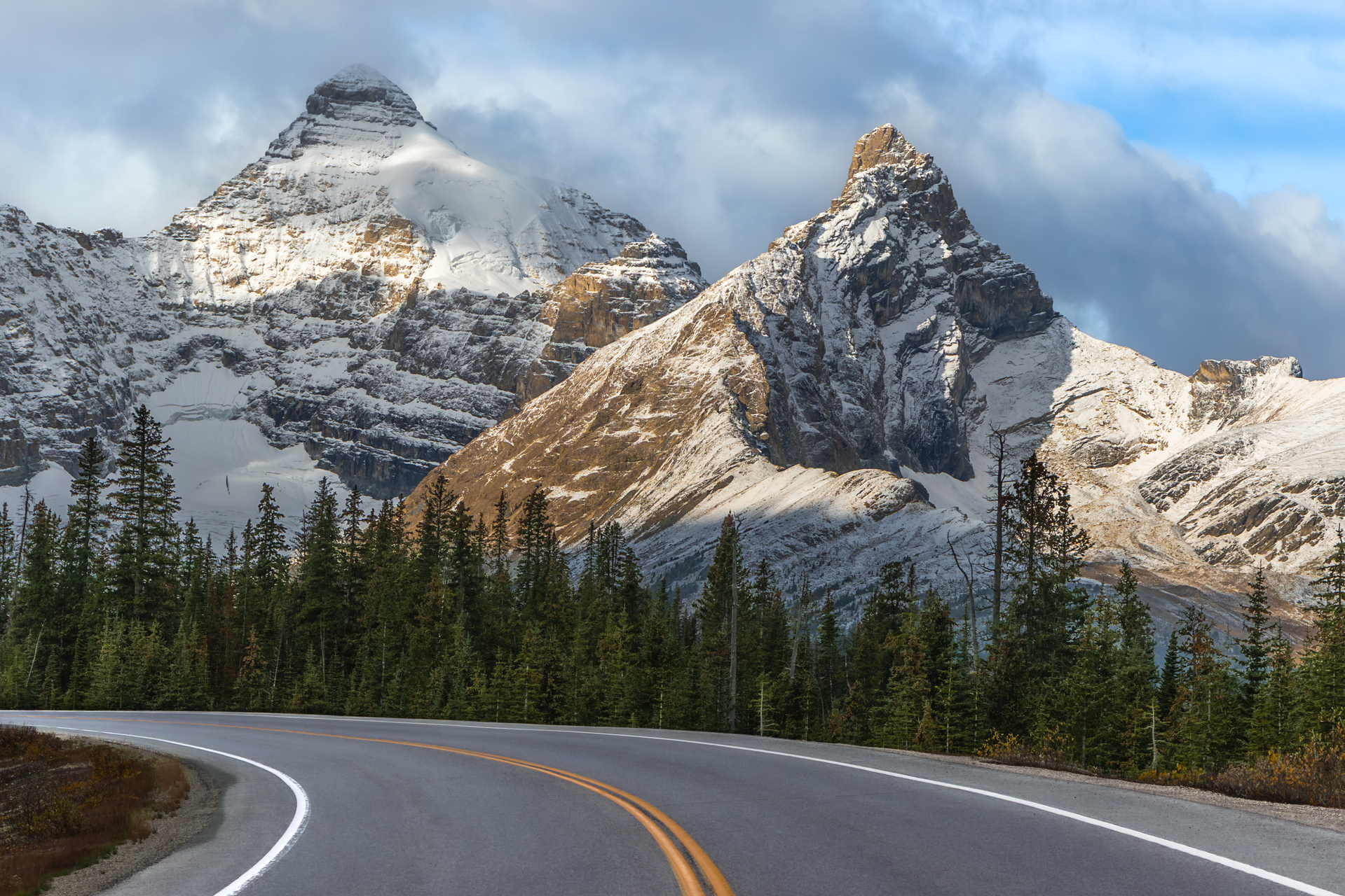 A winding mountain highway leads through an alpine forest toward dramatic, snow-covered peaks along the Icefields Parkway in Alberta, Canada. This iconic stretch of road connects Jasper and Banff National Parks and is renowned for its stunning landscapes. The empty road evokes themes of solitude, freedom, and exploration, ideal for concepts of road travel, adventure, and scenic wilderness.
Keywords: