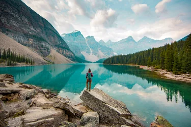 A woman standing on a scenic lookout overlooking Moraine Lake in Alberta, Canada.