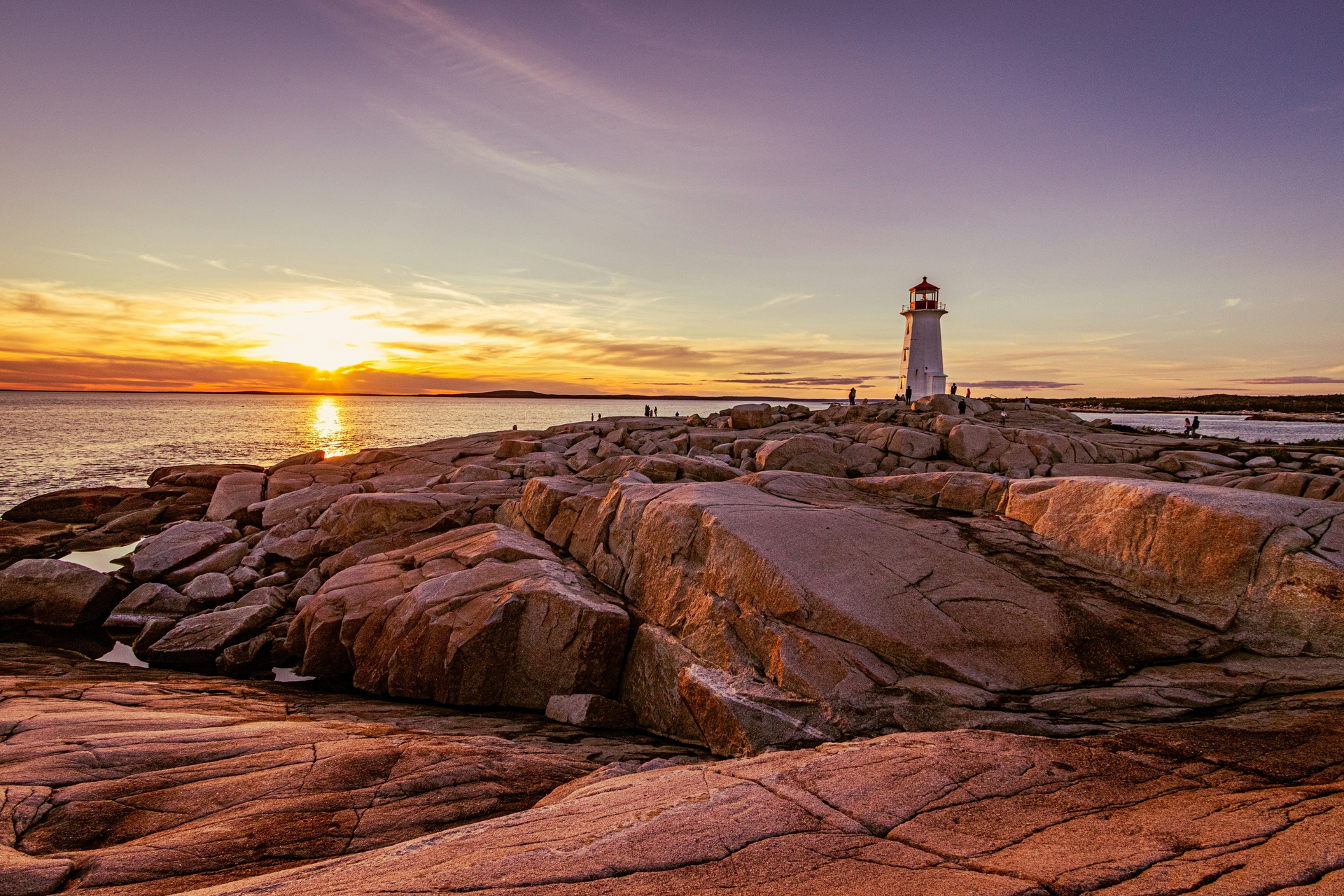 Smooth rocks on ocean shoreline of Peggy's Cove with Peggy’s Point Lighthouse in the province of Nova Scotia, Canada