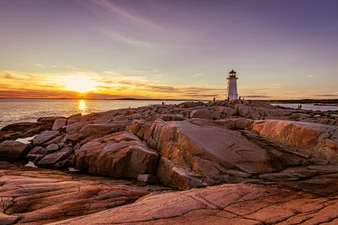 Smooth rocks on ocean shoreline of Peggy's Cove with Peggy’s Point Lighthouse in the province of Nova Scotia, Canada