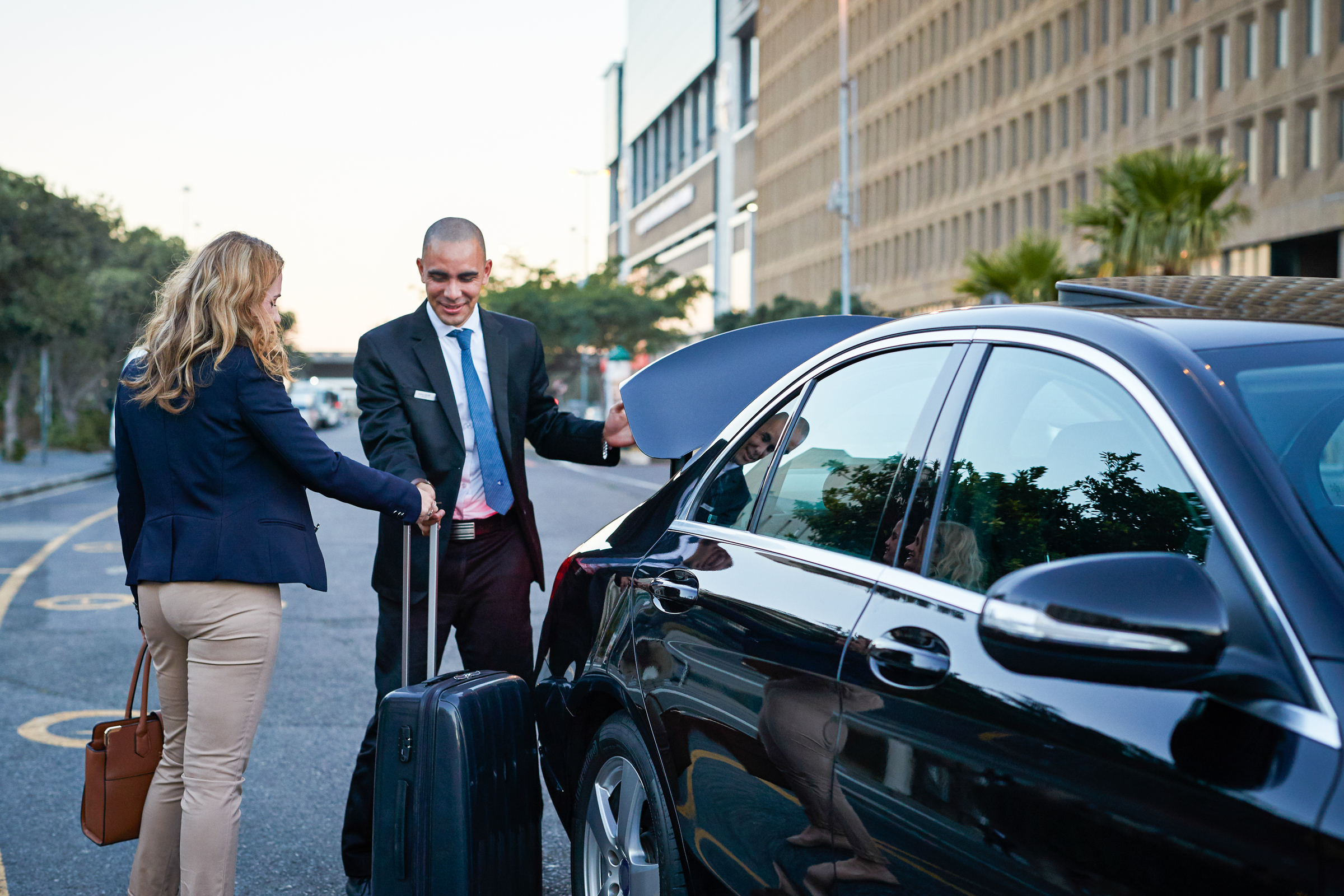 Driver assisting businesswoman into cab