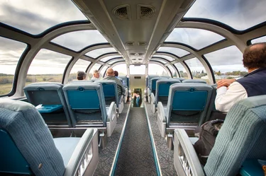 Passengers in the dome viewing area of the Skyline Car of The Canadian train, with cloudy sky above