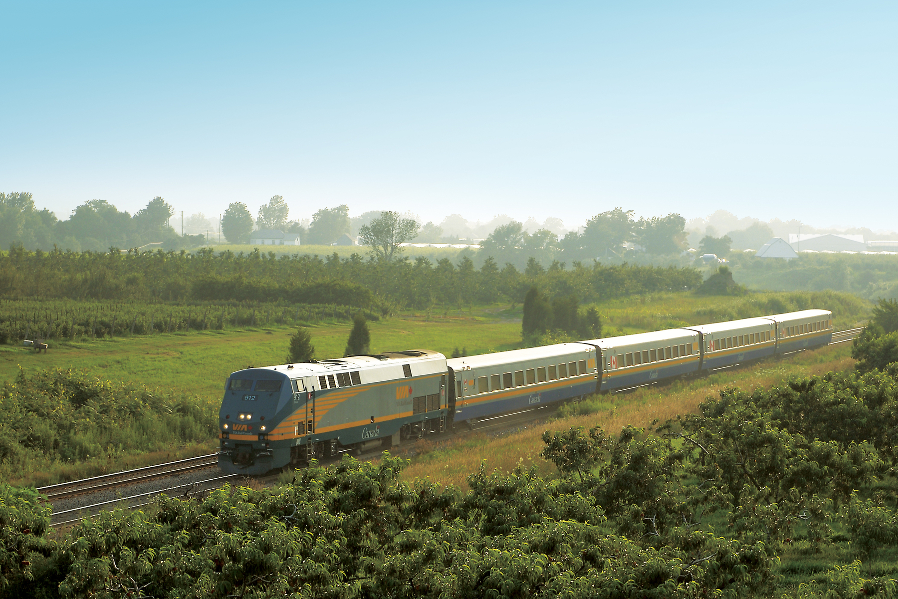 A train rolls through a green field on a clear day