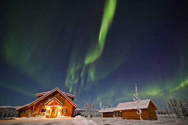 Northern lights in bright night sky by rustic cabins