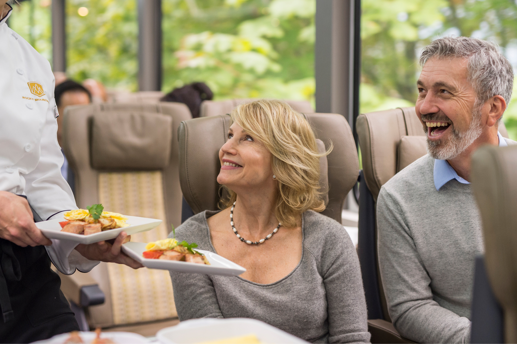 Chef serving breakfast to a couple in a SilverLeaf coach on the Rocky Mountaineer Vancouver to Banff train 