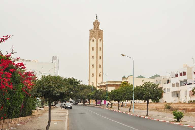 El imponente minarete de la Mezquita Mohammed V de Agadir visto desde una tranquila calle arbolada.