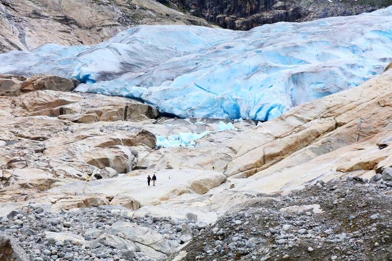兩個人在挪威尼加斯布倫冰川(Nigardsbreen)的藍冰附近漫步。