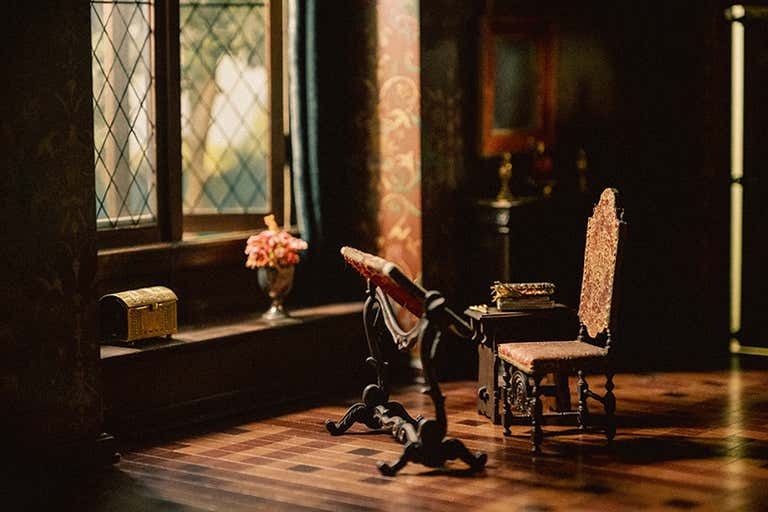 Escena de interior vintage con un escritorio de lectura junto a una ventana con cristales de rombos, una silla antigua y un cálido suelo de madera en un edificio histórico de Chicago.