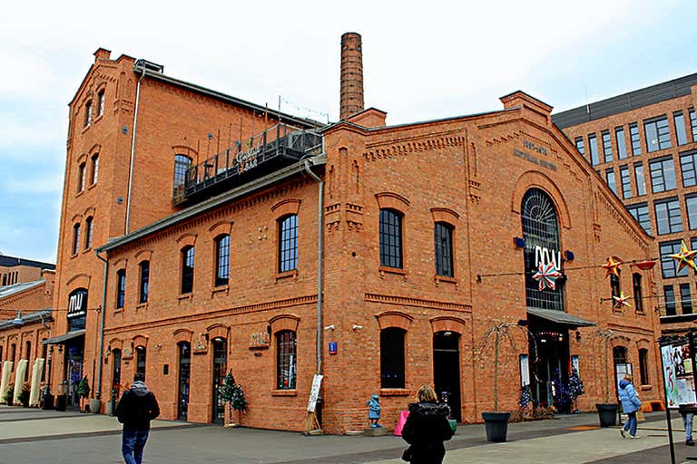 O exterior do Polish Vodka Museum, um prédio histórico de tijolos vermelhos com uma chaminé alta.