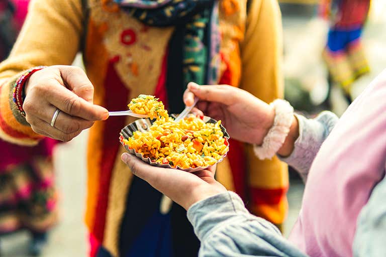 Duas pessoas compartilhando um prato de comida de rua em um ambiente vibrante.