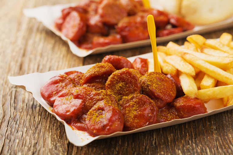 Currywurst with fries served on a wooden table
