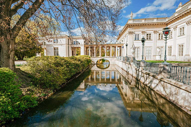 O canal que circunda o palácio no Parque Lazienzki com o palácio refletido na água.