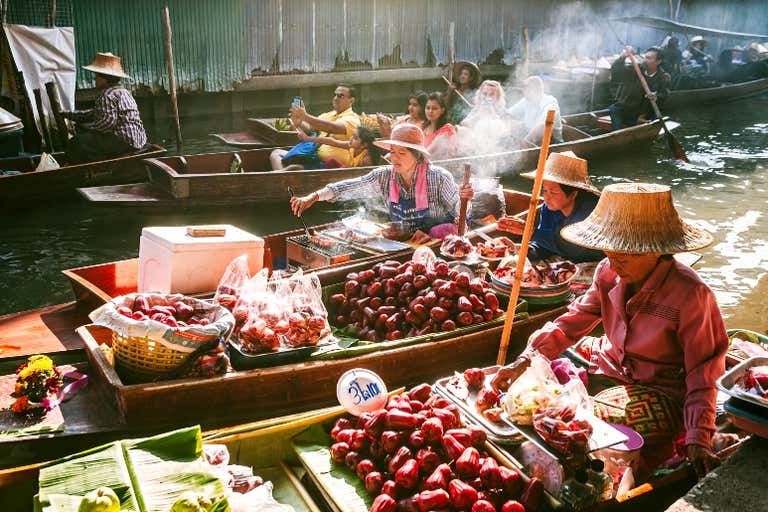 Traditional floating market vendor selling fresh fruits and grilled food from wooden boat, authentic Thai cultural experience