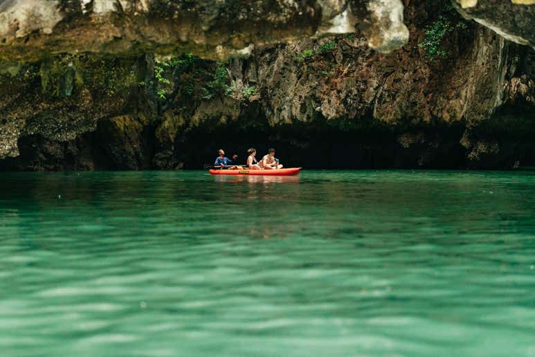 В заливе Пханг-Нга, недалеко от Пхукета, Таиланд, каякисты проплывают на каноэ через известняковые морские пещеры.