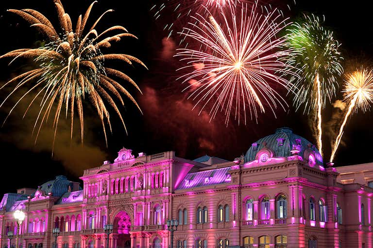 Casa Rosada illuminated in pink with fireworks display during New Year celebration.