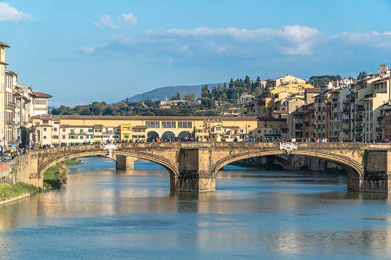 Een historische stenen brug in Florence met bogen en gebouwen aan beide zijden.