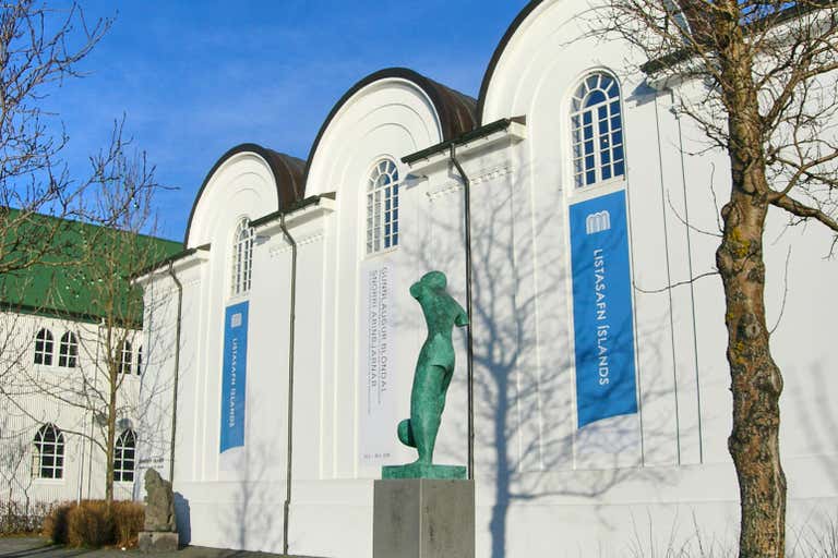 Vista exterior de la Galería Nacional de Islandia con una estatua delante.