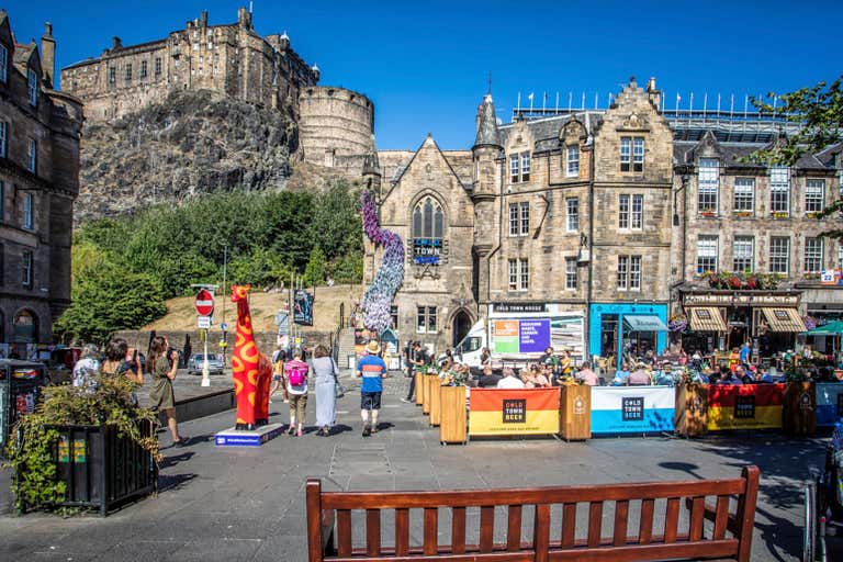A lively street scene in Edinburgh with Edinburgh Castle in the background.