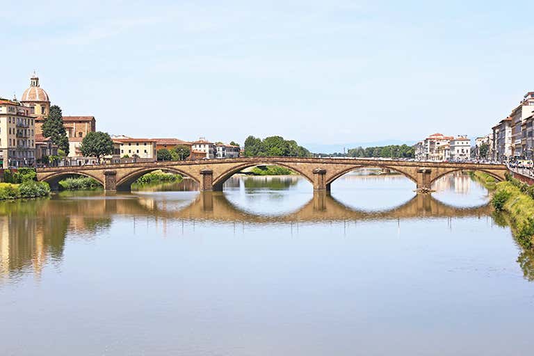 Een stenen brug met drie bogen overspant een rustige rivier in Florence.