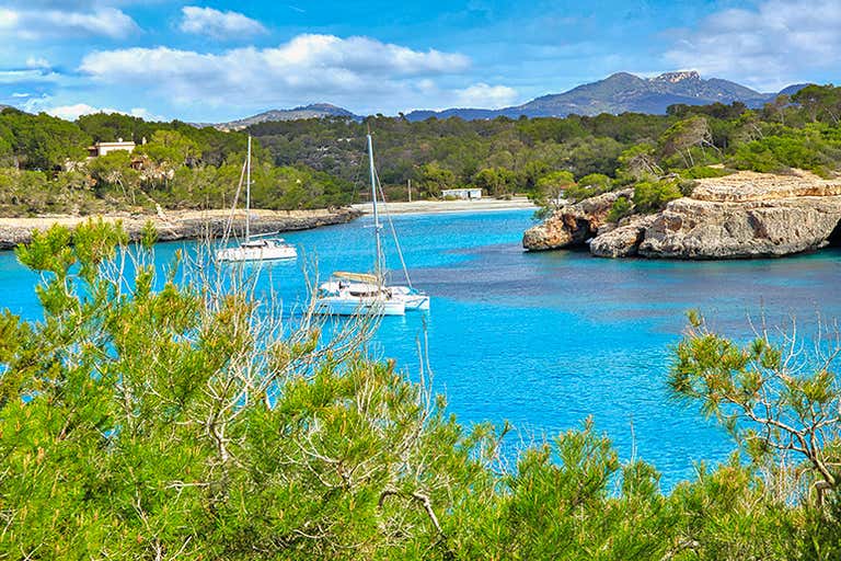 A picturesque bay in Mallorca with turquoise waters and sailboats.