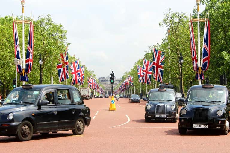 A view of The Mall in London with black cabs and Union Jack flags.