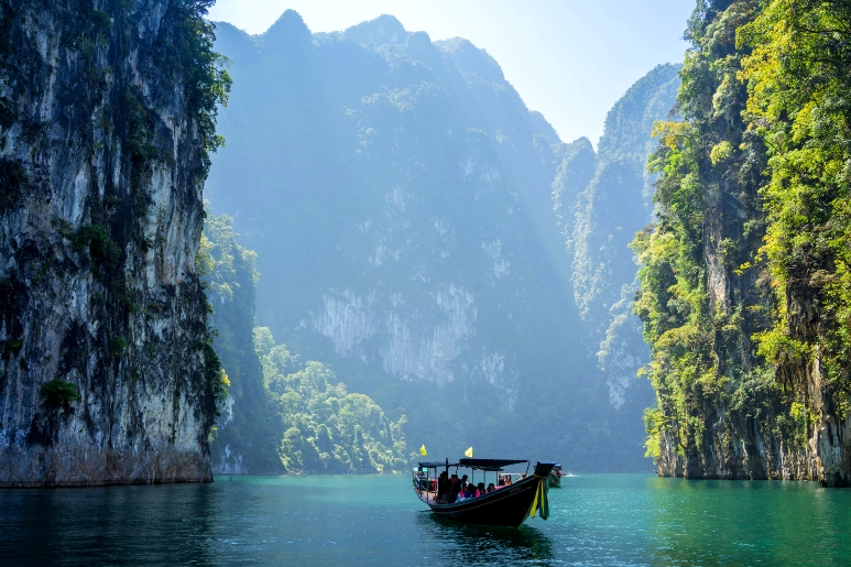 Лодка на чистой воде в окружении высоких скал — как на картине.