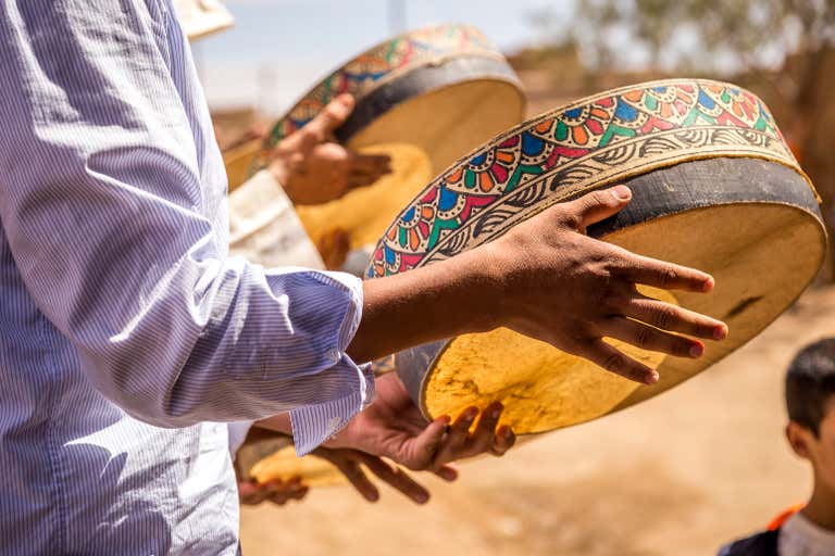 Primer plano de manos sujetando tambores tradicionales en Agadir.