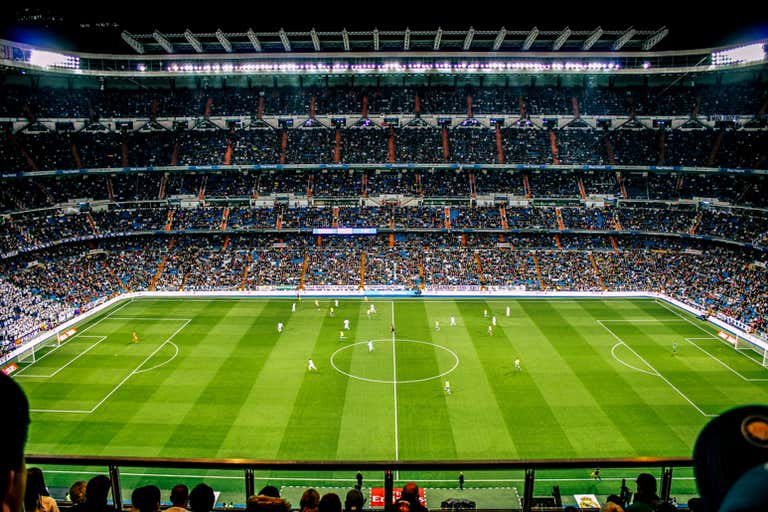 Uma partida de futebol acontecendo em um grande estádio cheio de espectadores.