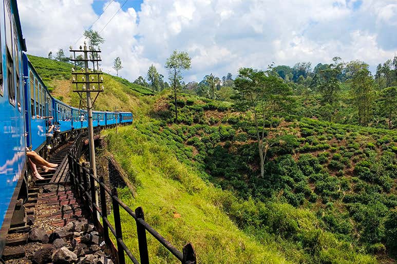 Blue train winding through tea plantations on the Kandy Route in Sri Lanka.