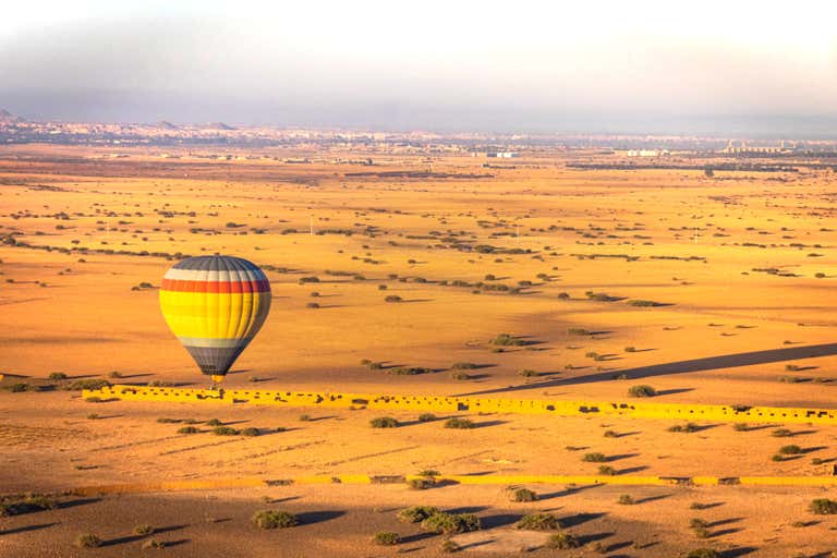 Un globo aerostático flota sobre un vasto paisaje desértico cerca de Marrakech.