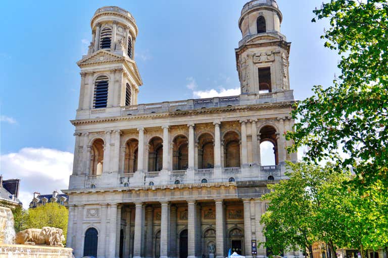 Interior of Saint-Sulpice with soaring arches, blue-tinted walls, Delacroix frescoes and golden altar in soft lighting