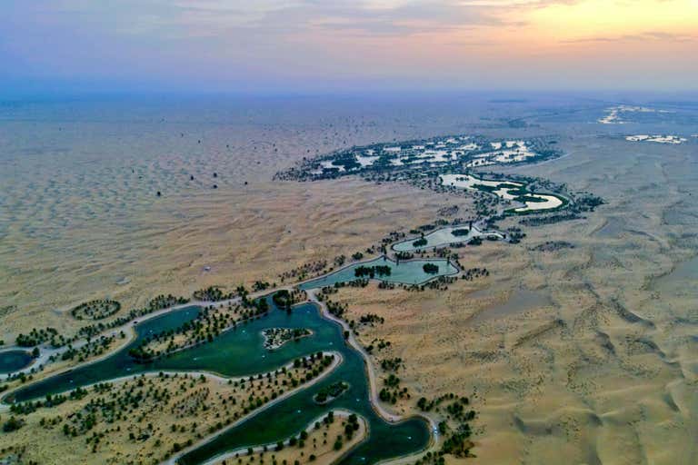 Aerial view of Al Qudra Lakes in Dubai at sunrise, with desert landscape.