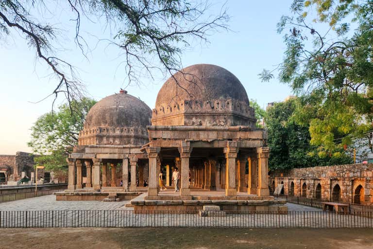 Uma estrutura histórica de pedra com cúpulas em um cenário de parque.