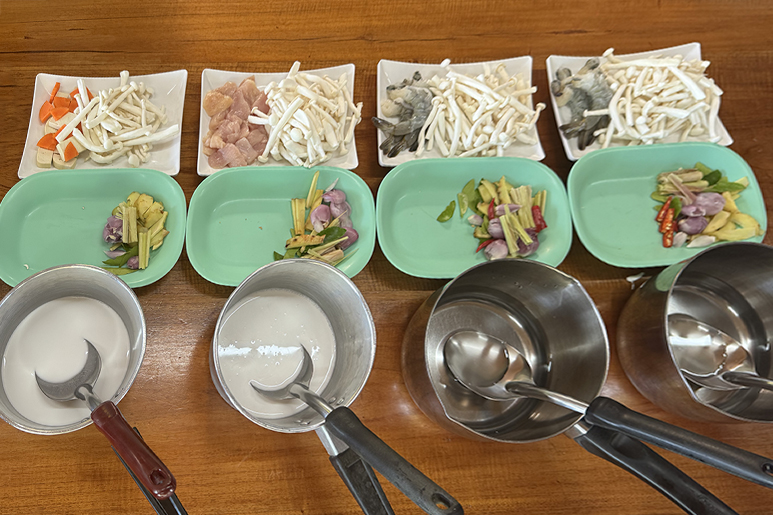 Стол, накрытый свежими продуктами — креветками и курицей с тайскими травами и овощами — во время тайского кулинарного мастер‑класса.